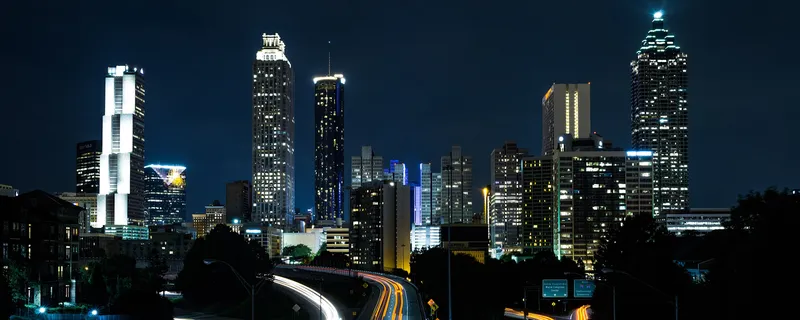 The Atlanta skyline at night from the Jackson Street Bridge, with light trails on the freeway below