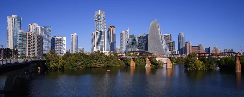 The downtown Austin skyline across Lady Bird Lake, with the graffiti-covered rail bridge over the water