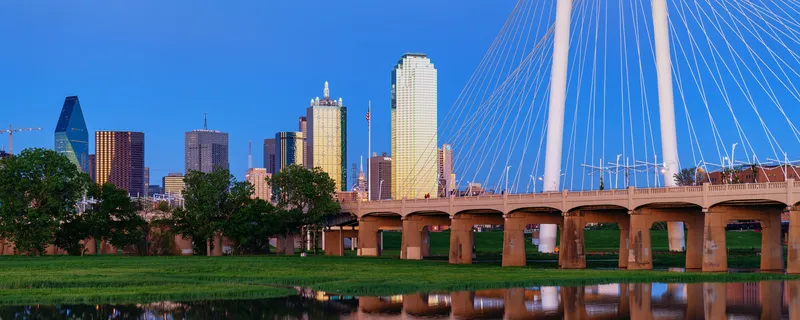 The Dallas skyline beside the Margaret Hunt Hill Bridge over the Trinity River at dusk