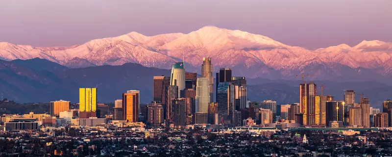 Downtown Los Angeles at sunset, with snow-capped Mount Baldy glowing pink behind it